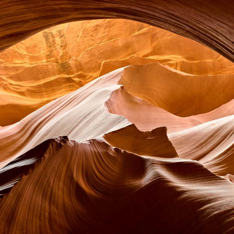Sunlit sandstone formations and sweeping layered rock inside Antelope Canyon.