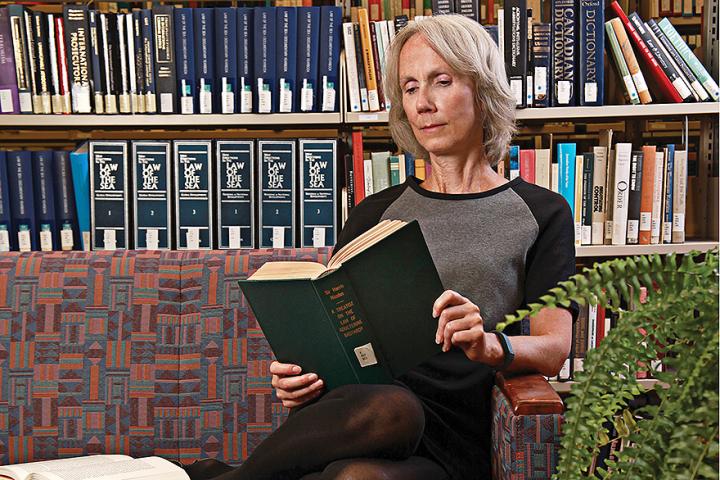 Dr. Martha Bailey curls up with a few good books, including The Laws of Adulterine Basterday, in the Lederman Law Library.