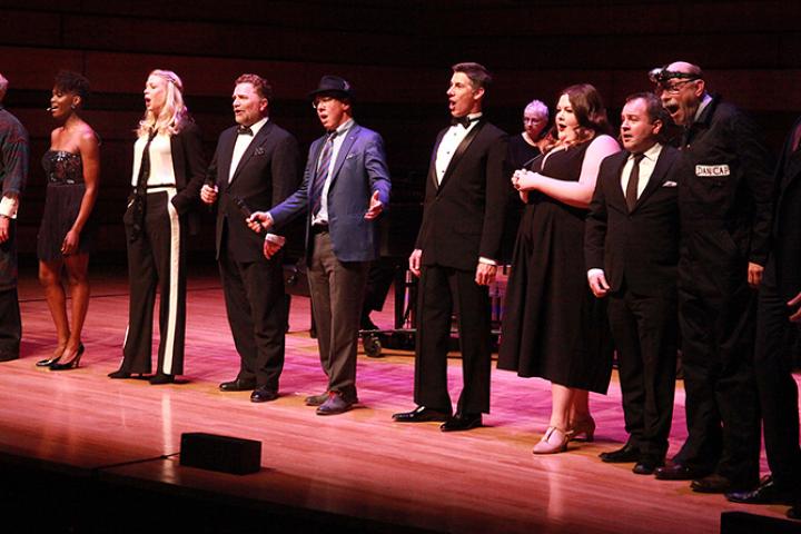 A nicely dressed group of people, singing, on stage at the Isabel