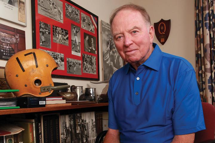 Cal Cal Connor, Arts’62, Meds’66, stands beside bookcase with football helmet.