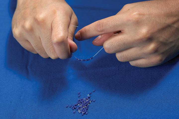 Hands beading a capital letter Q