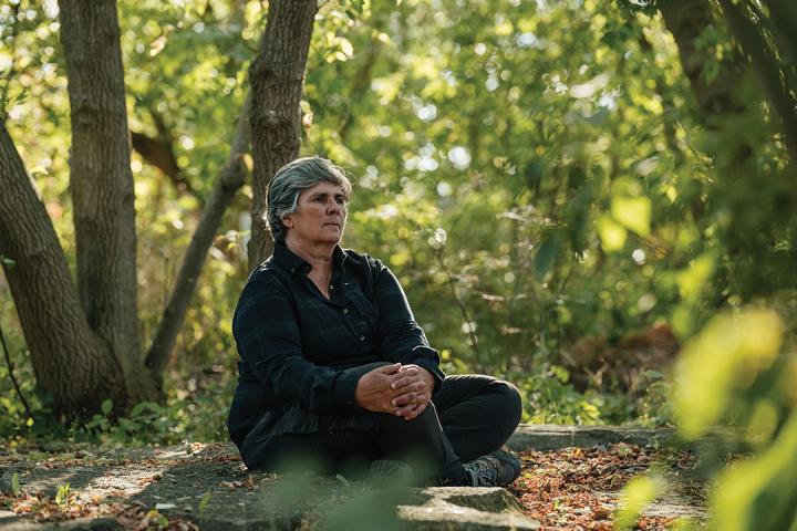 Woman sitting cross legged on the ground in the woods.