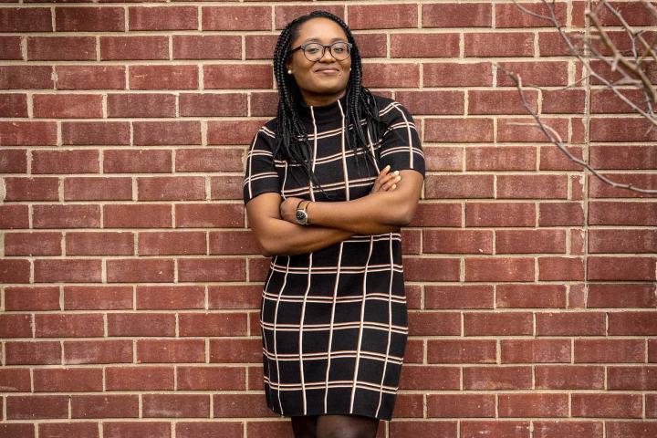 Dr. Idara Edem leaning against a brick wall with her arms crossed in front of her.