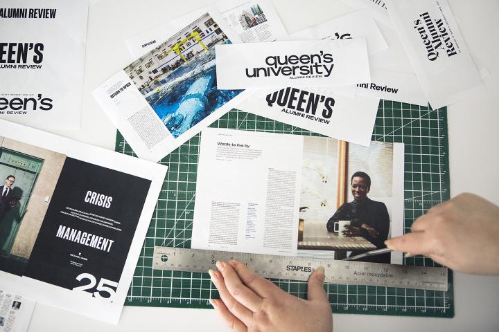 A woman cutting a printed magazine layout on a cutting board.