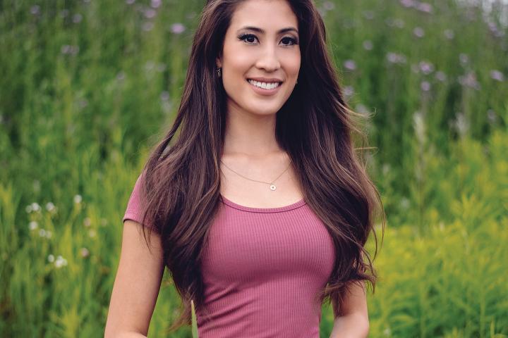 Photo of Miranda Anthistle standing in a field of wildflowers.
