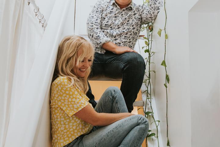 Taes Leavitt (Artsci’04) and Nick Adams (Artsci’04 and Ed’05), Splash N Boots, sit on the stairs in a stairwell. Long plant vines fall down a stairwell wall. 