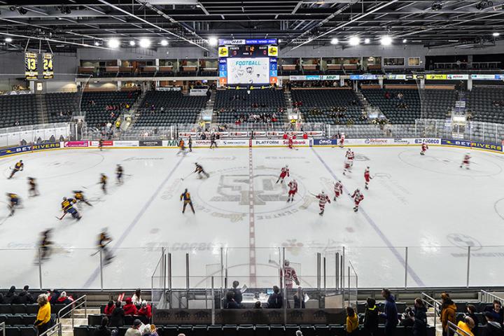 Two hockey teams warming up before the game in an arena.