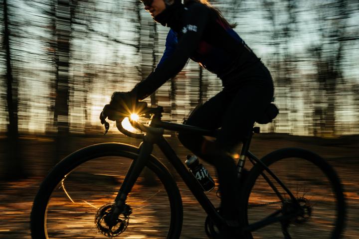 Woman riding her bicycle with sunsetting in the background.