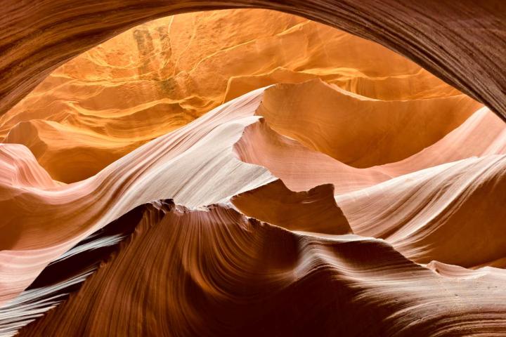 Sunlit sandstone formations and sweeping layered rock inside Antelope Canyon.