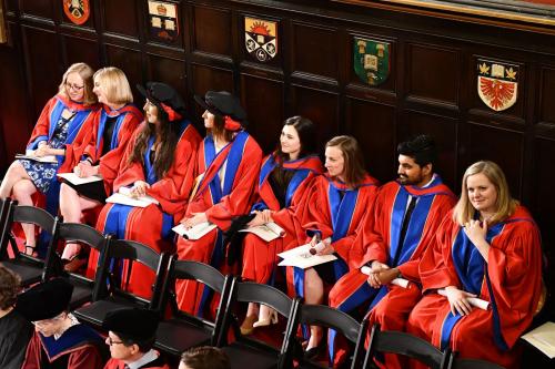 Eight people sitting in a row at a graduation ceremony