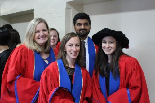 Four people smiling at a graduation ceremony