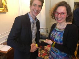 Two people smiling, one is holding an award