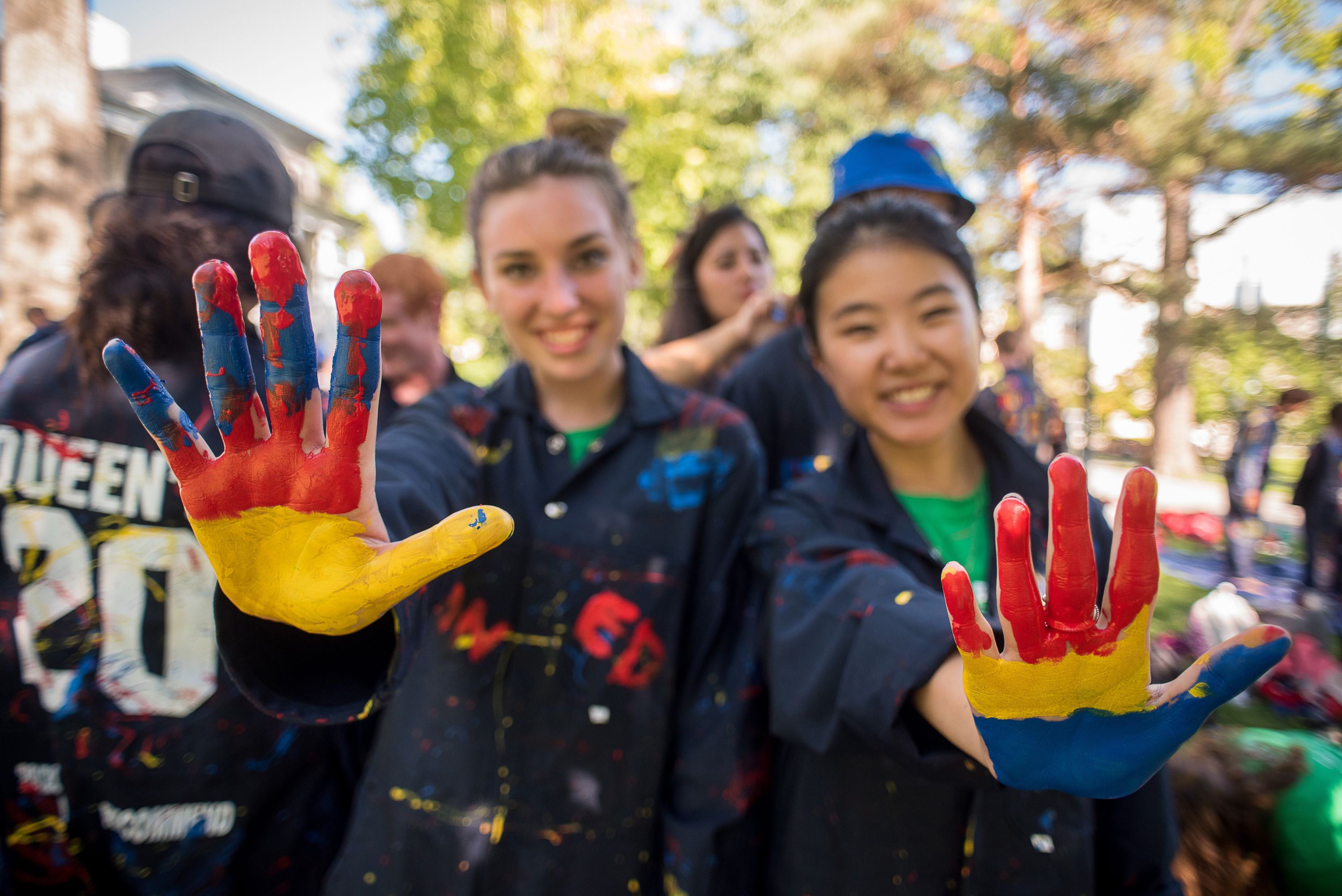 Two Queen's students holding out their hands painted with red, blue and yellow.
