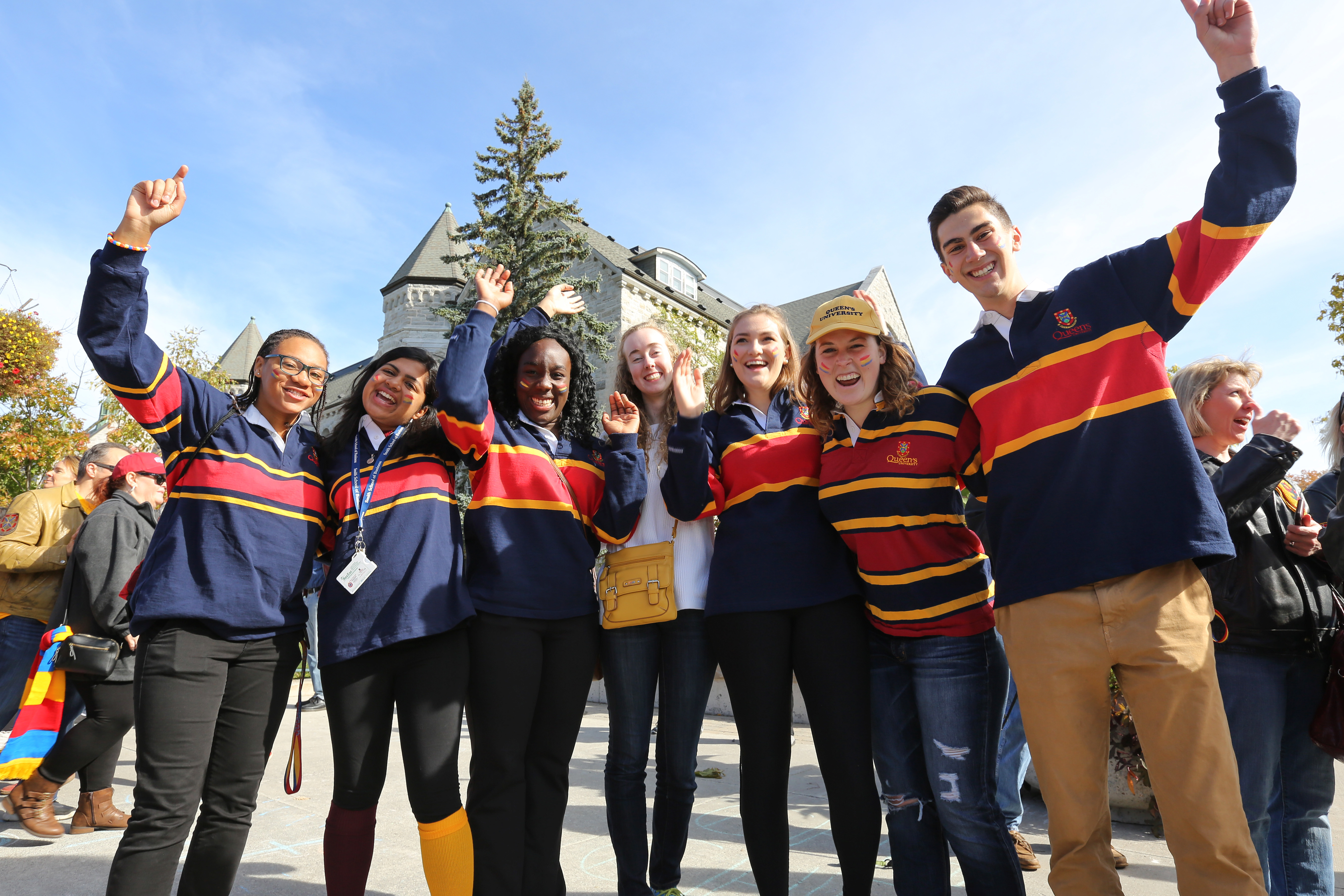 A group of Queen's students standing in a line and cheering.