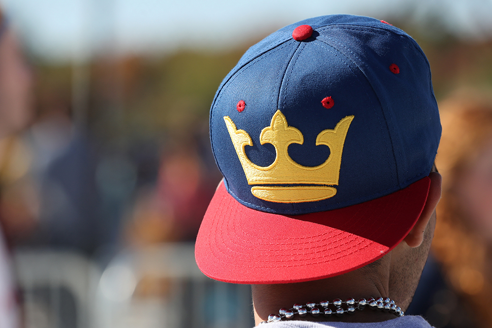 The back of a students head wearing a Queen's hat with blue body, red beak and a yellow crown.