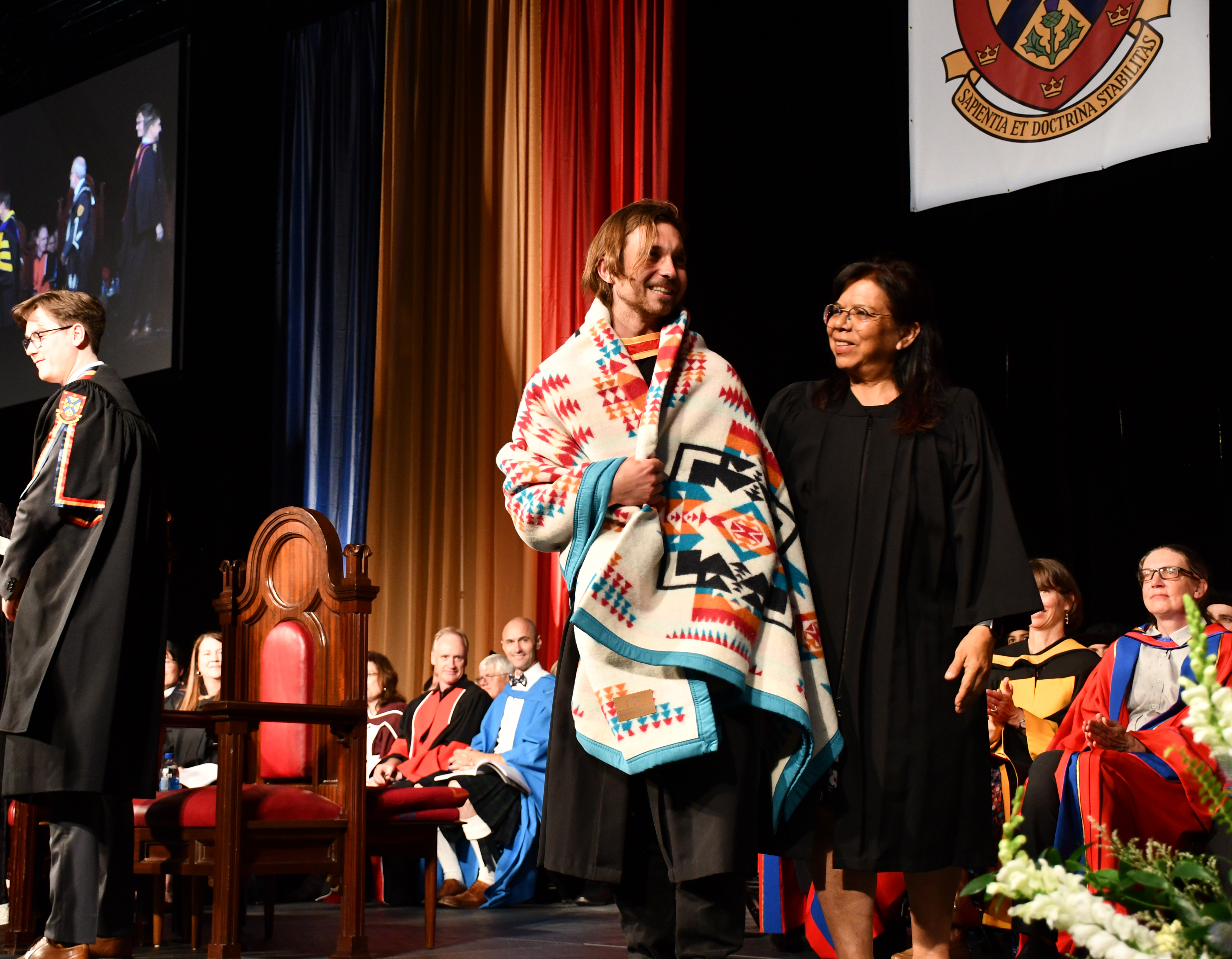 Indigenous student receiving a blanket at convocation.