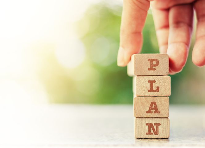 A hand placing a stack of blocks that says PLAN