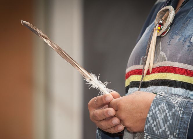 indigenous person holding a feather