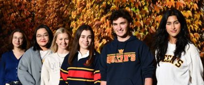 Students standing in front of a wall covered in orange leaves.