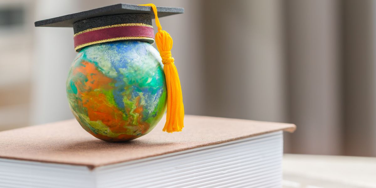 A globe with a graduation hat sits on top of a book.