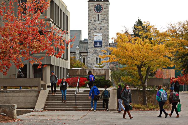 Students walking on Queen's campus in the winter. Grant Hall Tower in the background.