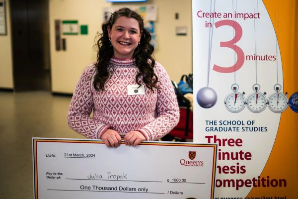 Student Julia Tropak holding a large cheque.