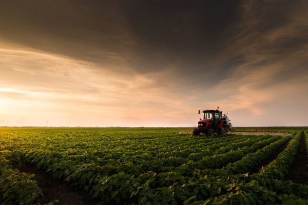 A tractor in a field with a sunset behind it