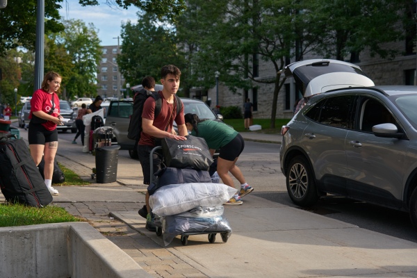 An incoming student moving his belongings toward his residence building during move-in 2022.
