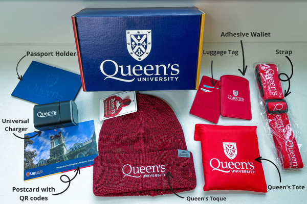 A Queen's University box with items including a red toque, tote bag, lanyard and postcard.