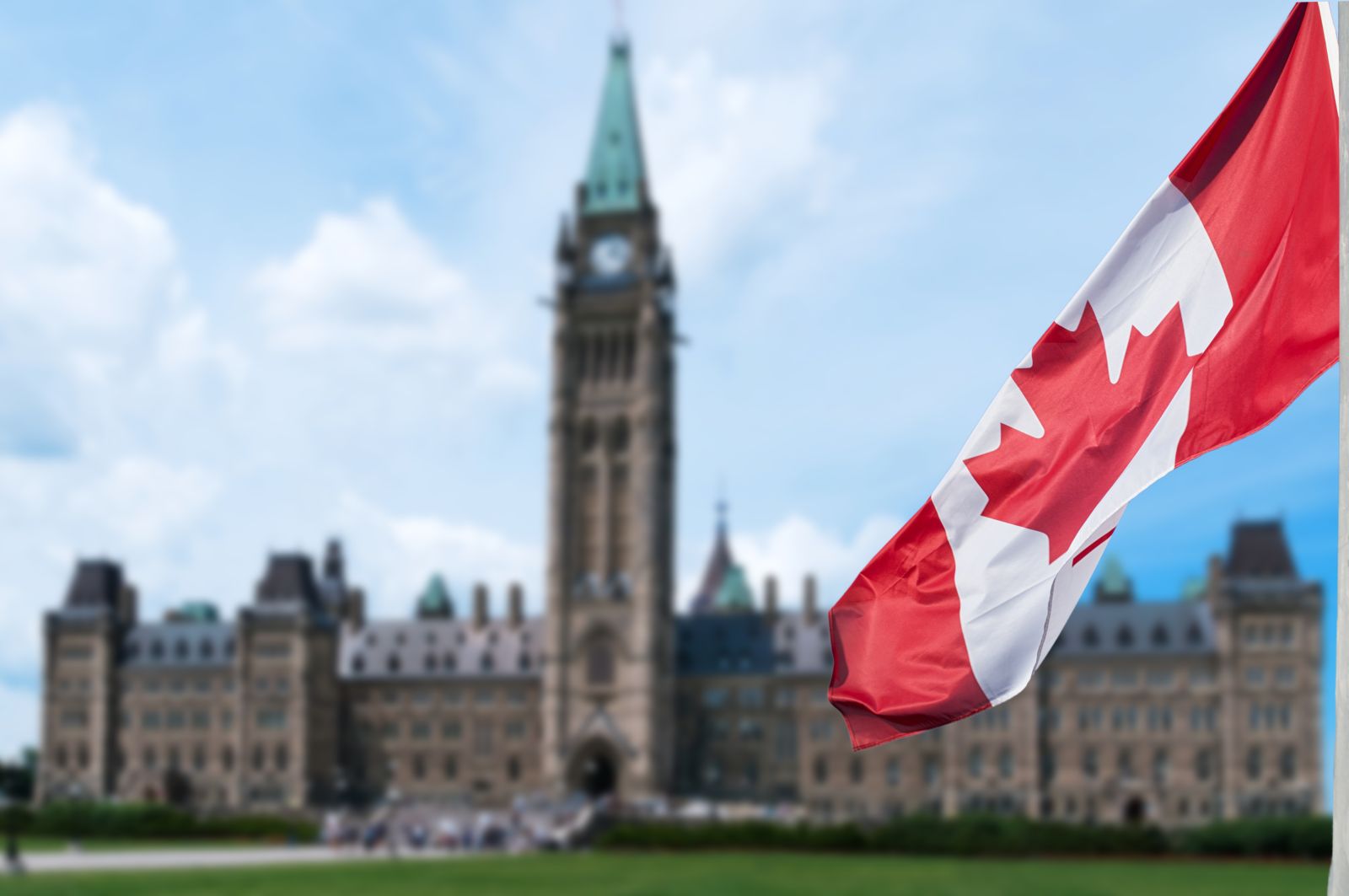 Canadian flag waving with Parliament Buildings hill in the background