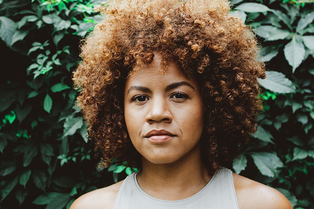 Britta B standing in front of a wall of leaves.