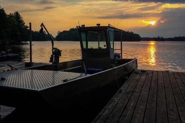 A small boat at a dock at sunset.