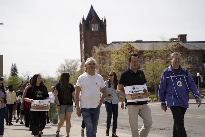 Elder-In-Residence Allen Doxtator, left, Associate Director of the Office of Indigenous Initiatives Aaron St. Pierre, and Provost and Vice-Principal (Academic) Mark Green lead Queen's community members on the advocacy walk in support of the Moose Hide Campaign. (Queen's University)