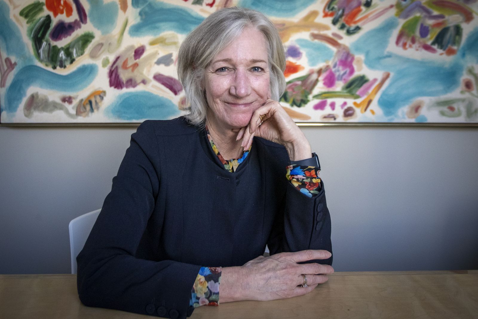 Dean Barbara Crow sitting in front of a painting