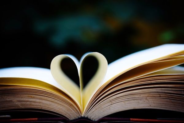 An open book with two pages folded together to form a heart.