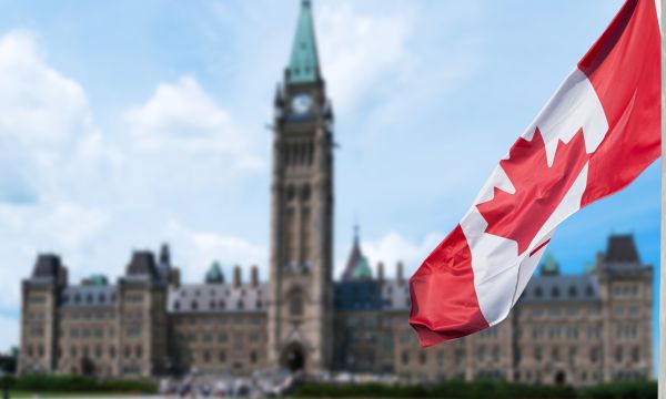 Canadian flag waving with Parliament Buildings hill in the background