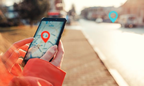 Female hands hold smartphone with maps app, and marked location icon, red and blue destination icon