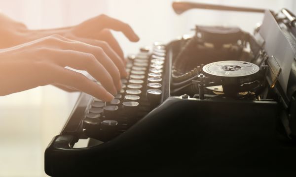 woman's hands writing on a typewriter