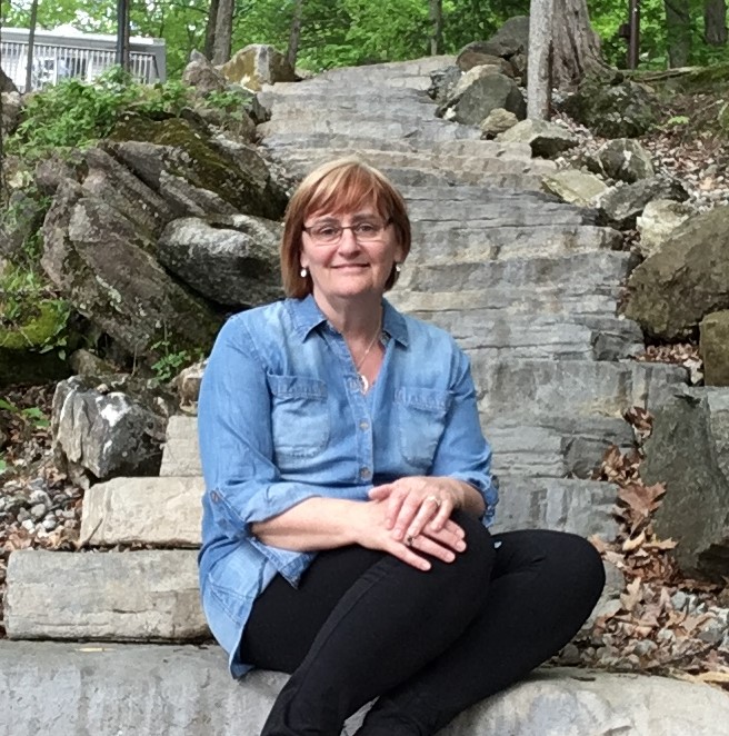 "Kim Buitenhuis sitting on stone steps outdoors."