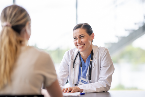 a person across a desk from another person in a white physician's lab coat