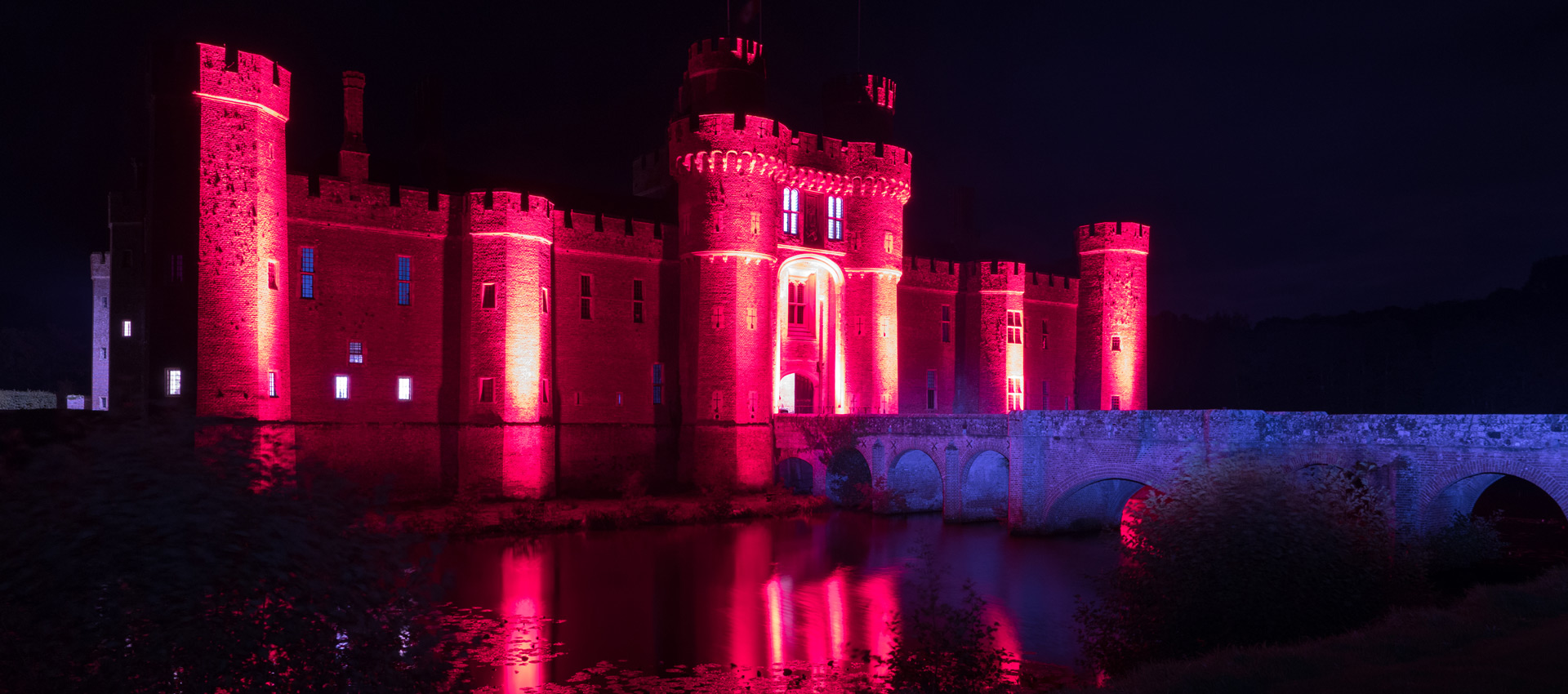 Herstmonceux Castle lit in red
