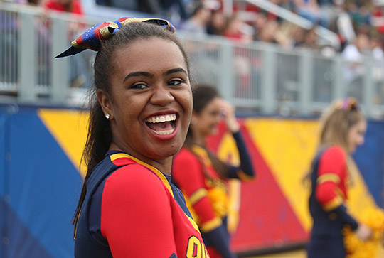 Queen's Cheerleader smiling at a football game