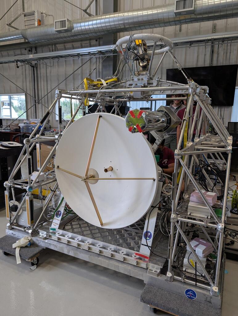 A radio telescope mounted on a large (1.5 meter high) aluminum balloon gondola.  There are many electronics boxes visible on the gondola.