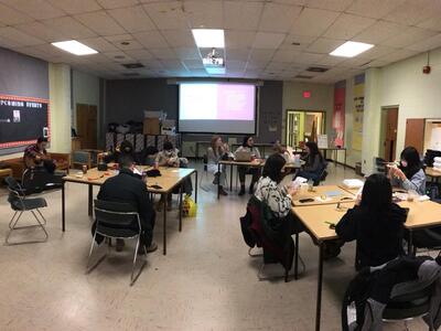 students sit around and embroider