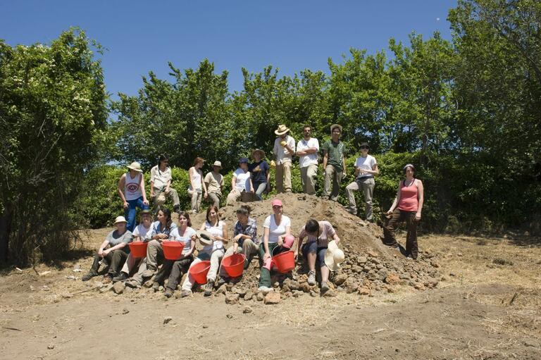 Caere dig team posing on a mound of excavated dirt.