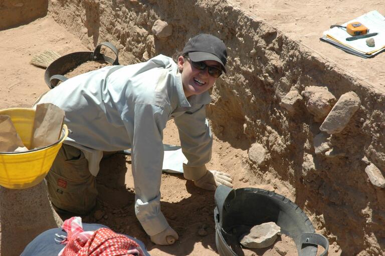 Student working carefully to clear a floor at Humayma excavation site.