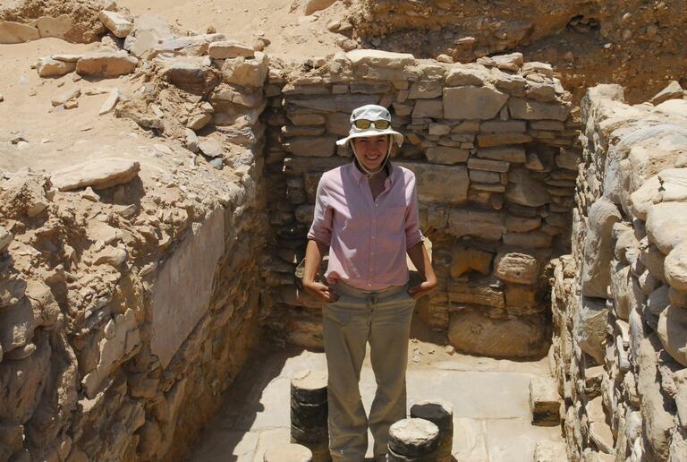 Student posing in a cleared room at Humayma excavation site.