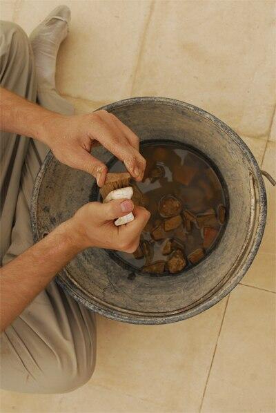 Student washing pottery sherds at Humayma excavation site.