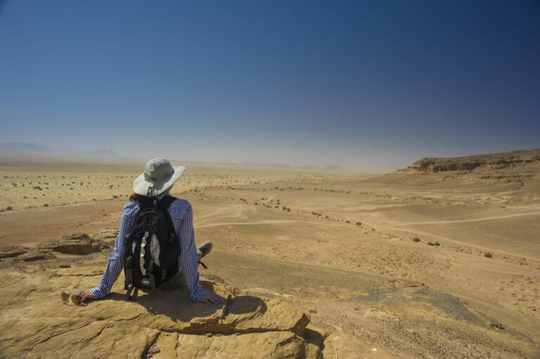 Student having a seat and taking a rest, overlooking the desert views near Humayma excavation site.