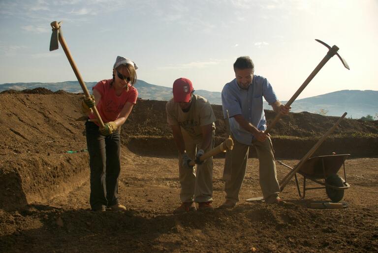 Dr. Colivicchi and two students digging with pick axes at Matera excavation site.